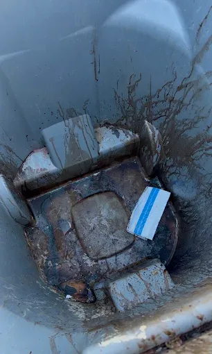Inside of a dirty gray trash can caked with grime before a Rad Cans cleaning