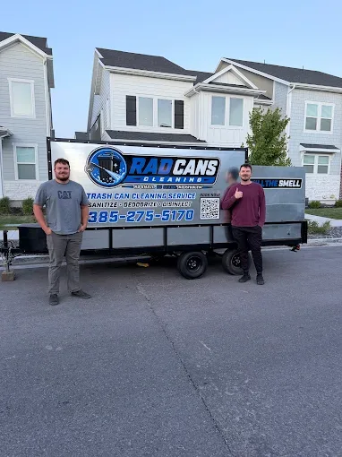 The two brothers who own Rad Cans Cleaning standing beside their trash can cleaning trailer in Utah